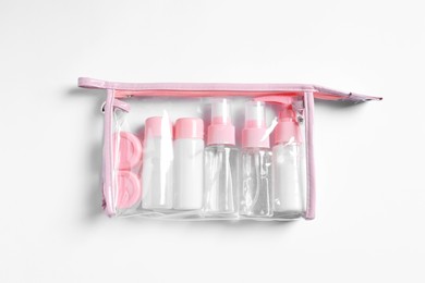 Photo of Cosmetic travel kit in plastic bag on white background, top view