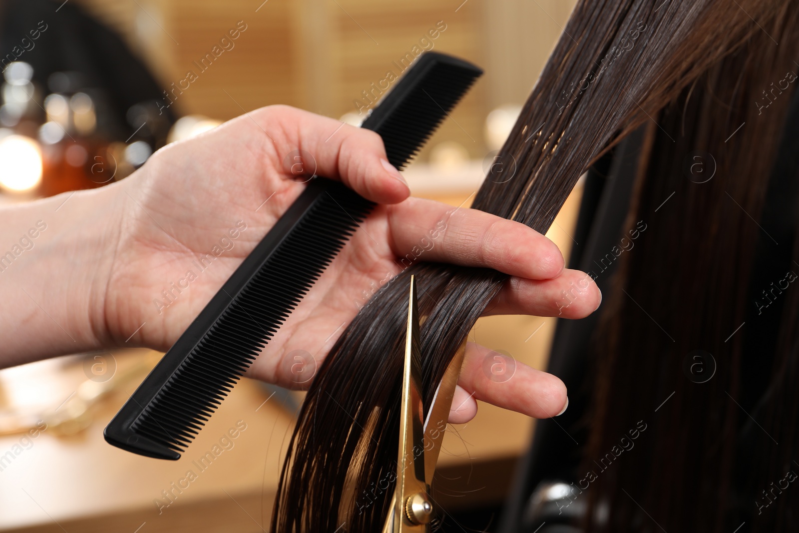 Photo of Hairdresser cutting client's hair with scissors in salon, closeup