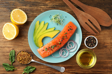 Photo of Delicious salmon with spinach and avocado served on wooden table, flat lay