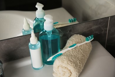 Photo of Light blue toothbrush, terry towel and cosmetic products in bathroom