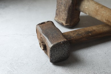 Two sledgehammers on grey background, closeup. Space for text