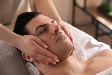 Photo of Man receiving facial massage in beauty salon, closeup