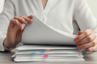 Woman reading documents at wooden table in office, closeup