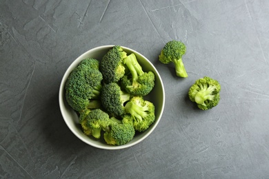 Photo of Bowl and fresh broccoli on grey table, flat lay