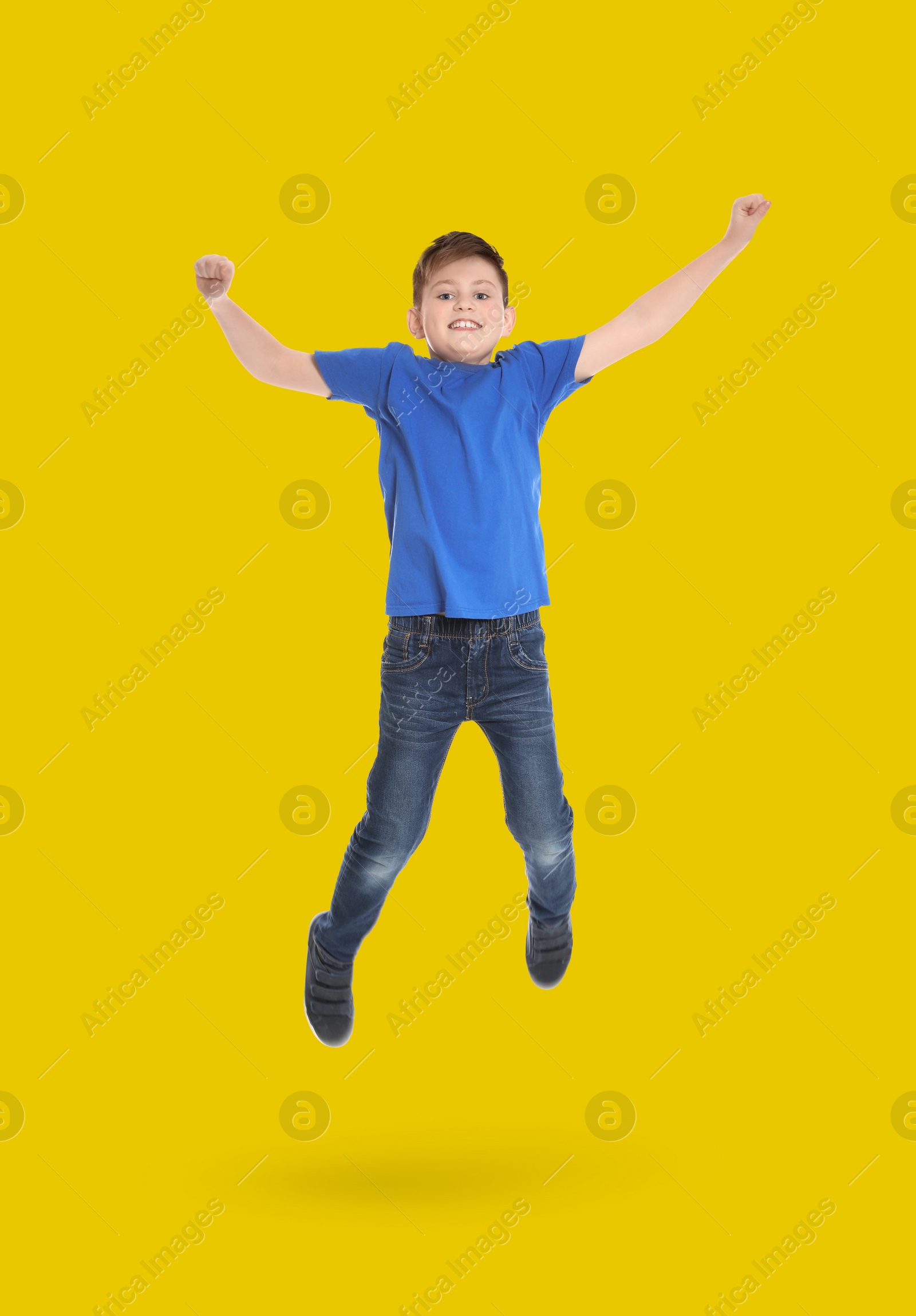 Image of Happy boy jumping on golden background, full length portrait