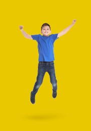 Image of Happy boy jumping on golden background, full length portrait