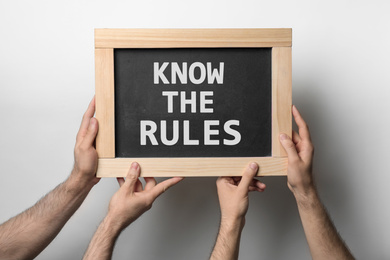 Image of Men holding chalkboard with phrase Know the rules on white background, closeup