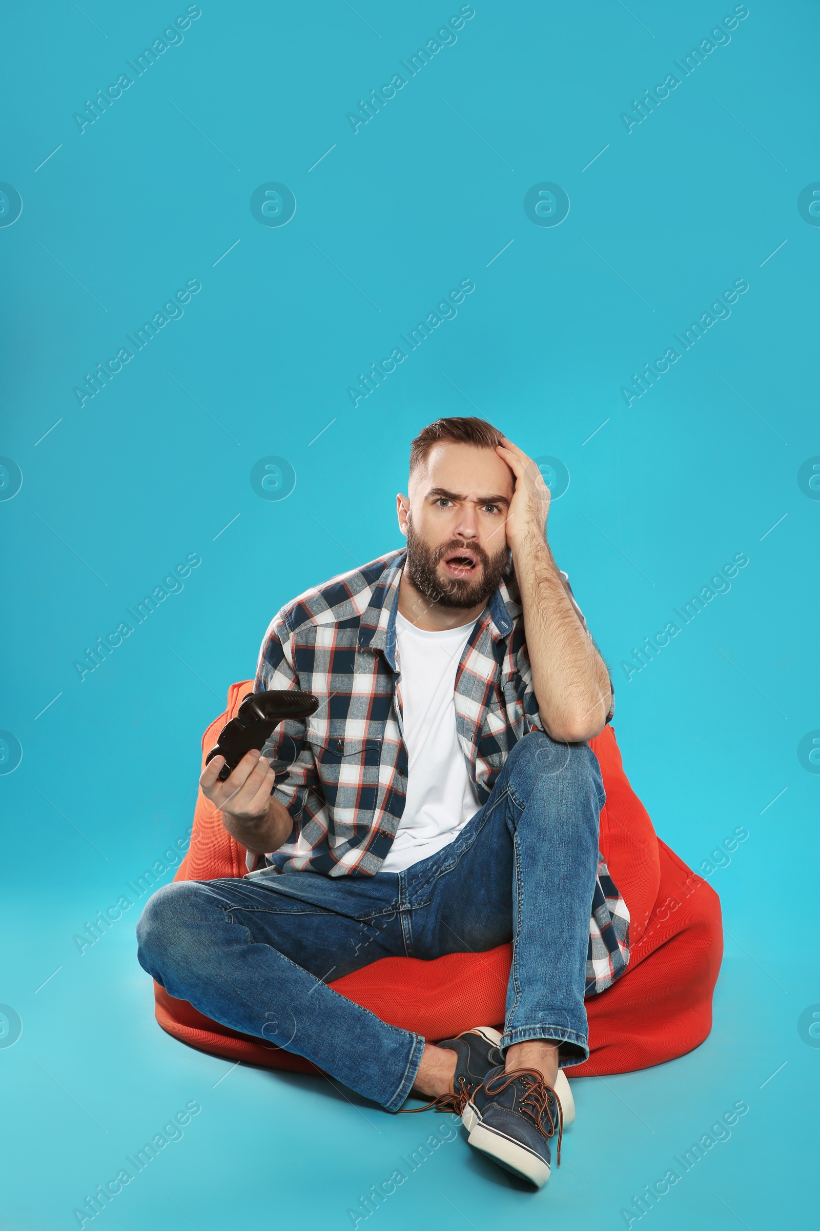 Photo of Emotional young man playing video games with controller on color background. Space for text