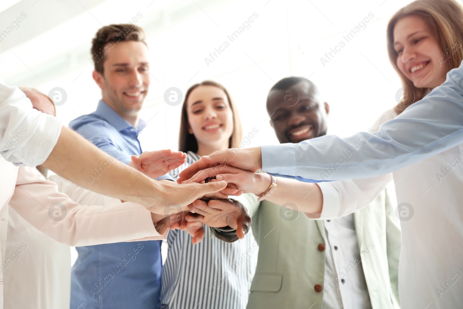 Photo of People putting hands together indoors. Unity concept