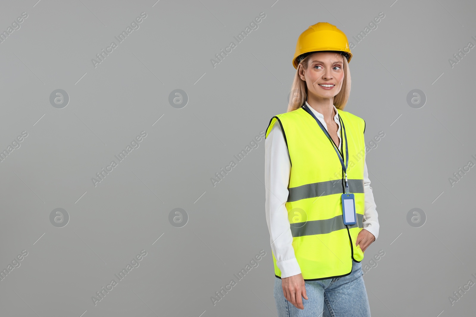 Photo of Engineer with hard hat and badge on grey background, space for text