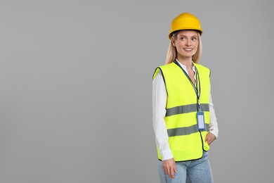 Engineer with hard hat and badge on grey background, space for text