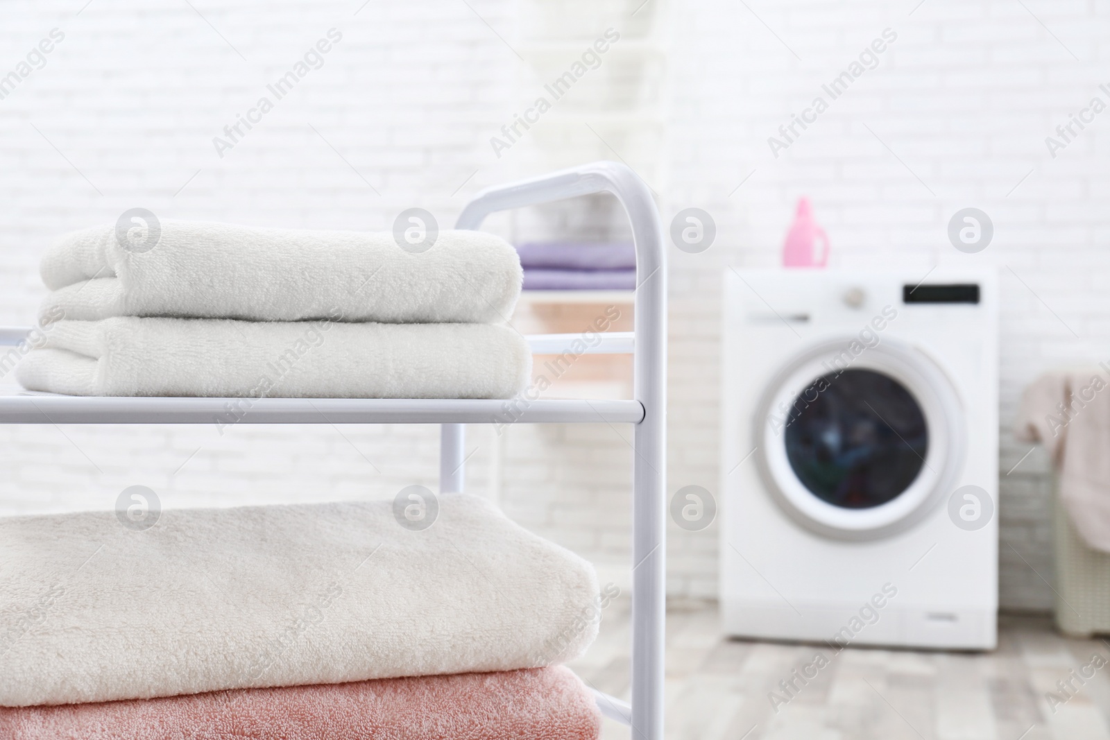 Photo of Folded clean terry towels on shelving unit in laundry room, space for text