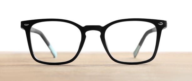 Photo of Stylish glasses with black frame on wooden table against white background