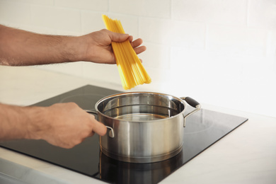 Man cooking pasta on stove in kitchen, closeup