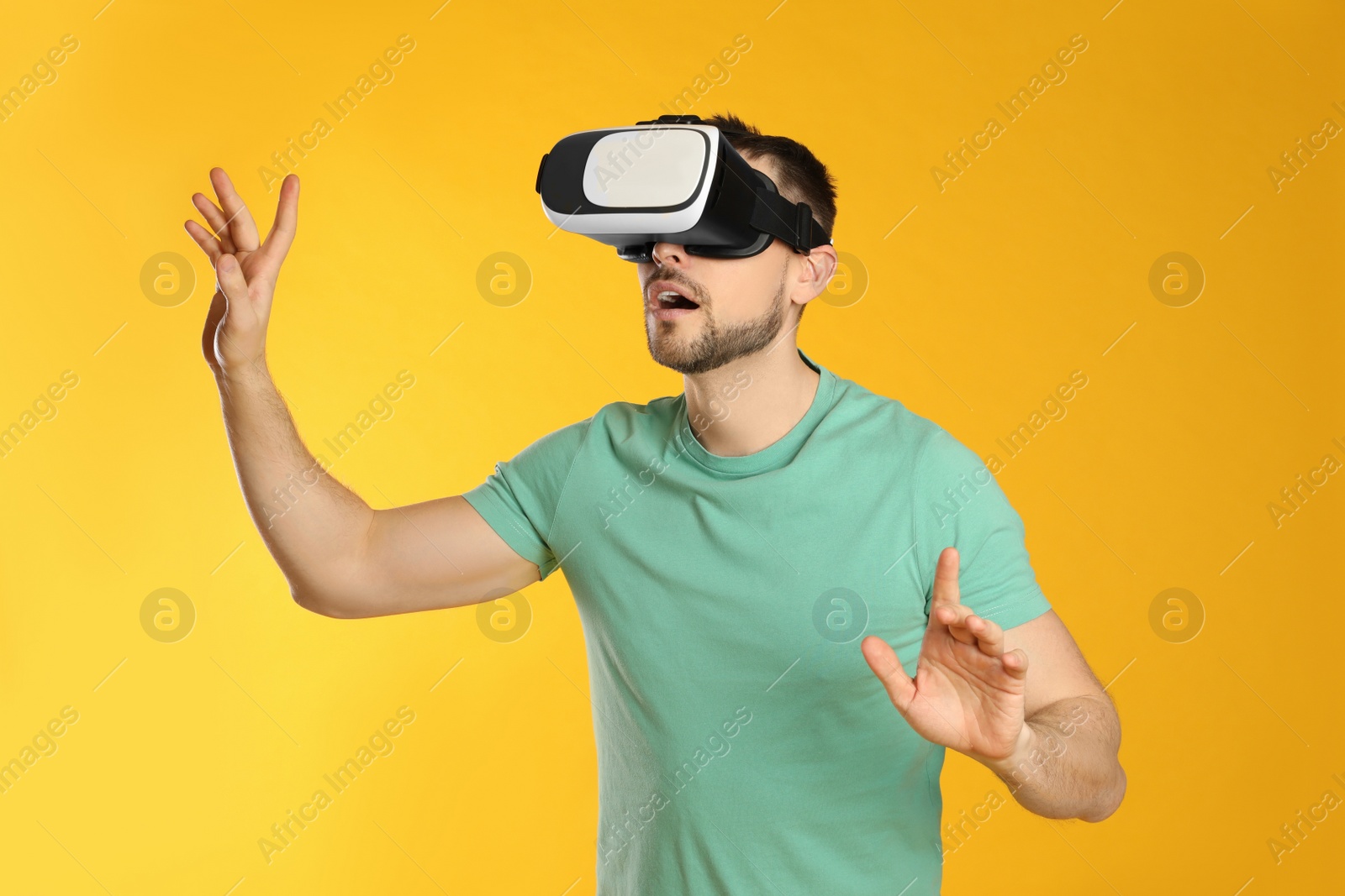 Photo of Man using virtual reality headset on yellow background