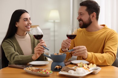 Photo of Affectionate couple enjoying chocolate fondue during romantic date at home