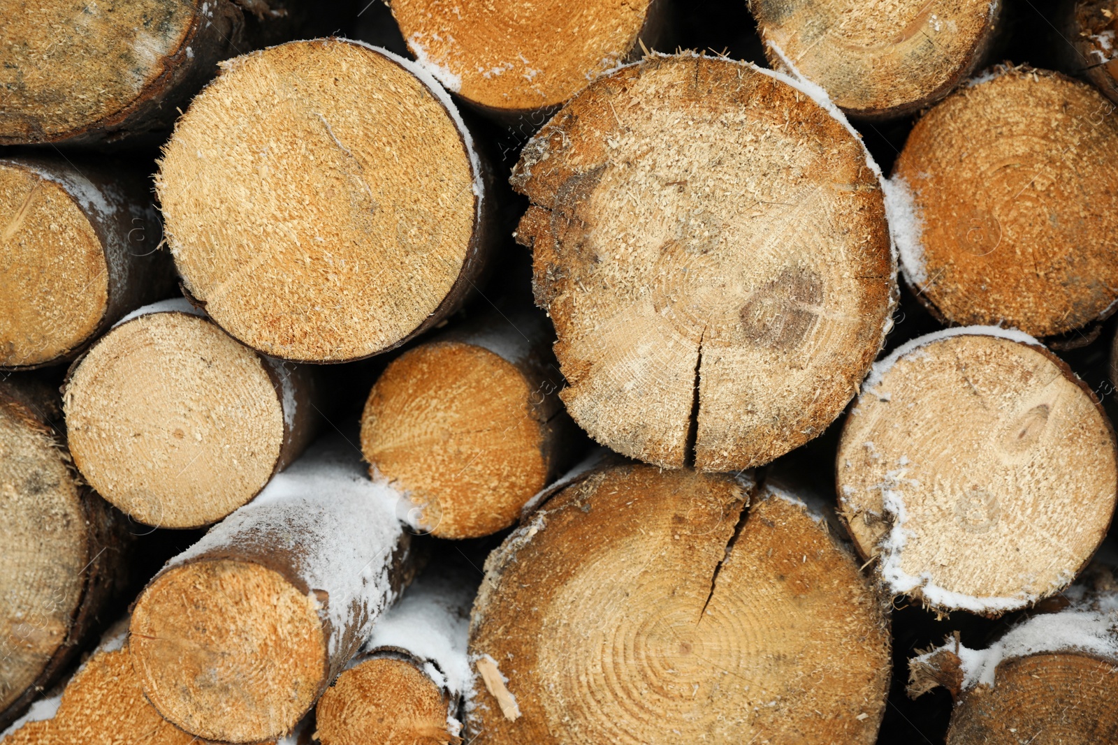 Photo of Stacked firewood with snow as background, closeup. Heating house in winter