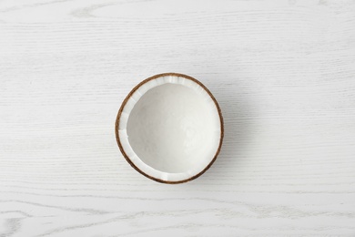 Photo of Half of coconut on white wooden background, top view