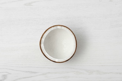 Half of coconut on white wooden background, top view