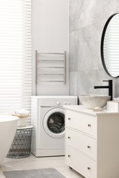 Stylish bathroom interior with heated towel rail and modern washing machine