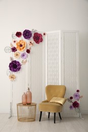 Photo of Beautiful photo zone with folding screen, chair and floral decor indoors