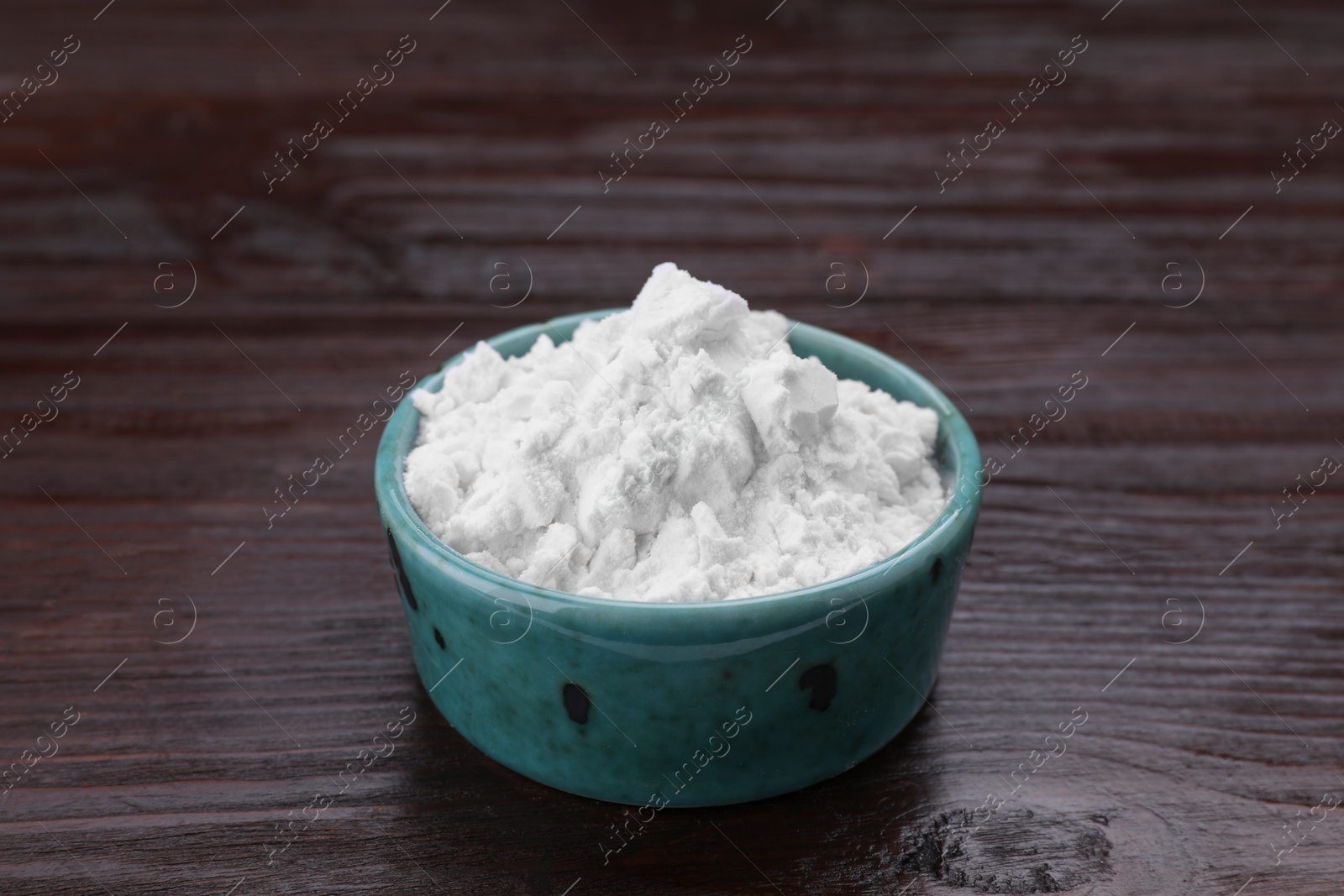 Photo of Starch in bowl on wooden table, closeup