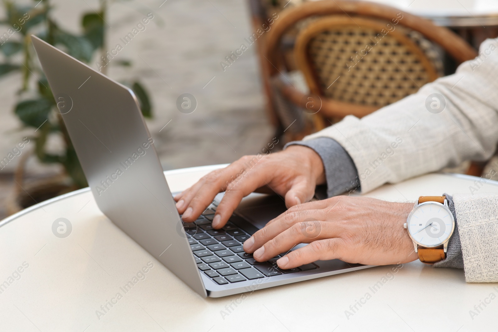 Photo of Man working on laptop at table in cafe, closeup