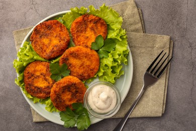 Tasty vegan cutlets served with sauce on light grey table, top view