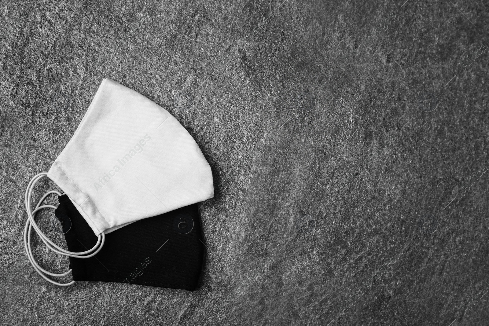 Photo of Homemade protective face masks on grey stone table, flat lay. Space for text