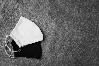 Homemade protective face masks on grey stone table, flat lay. Space for text