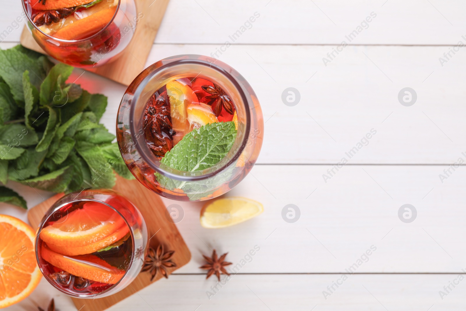 Photo of Delicious punch drink and ingredients on white wooden table, flat lay. Space for text