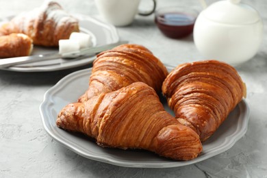 Photo of Tasty croissants served on light grey textured table, closeup