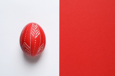 Creative red painted Easter egg on color background, top view. Space for text