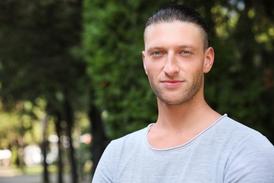 Photo of Portrait of handsome young man in park, space for text