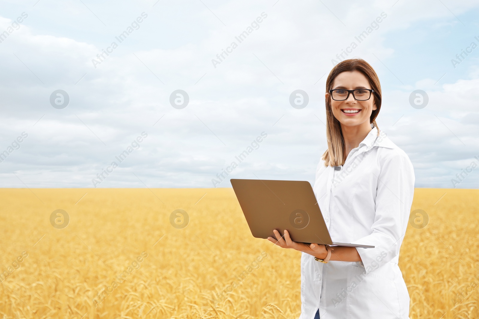 Photo of Young agronomist with laptop in grain field. Cereal farming