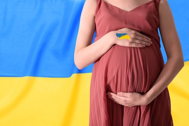 Image of Pregnant woman and Ukrainian flag on background, closeup with space for text. Stop war