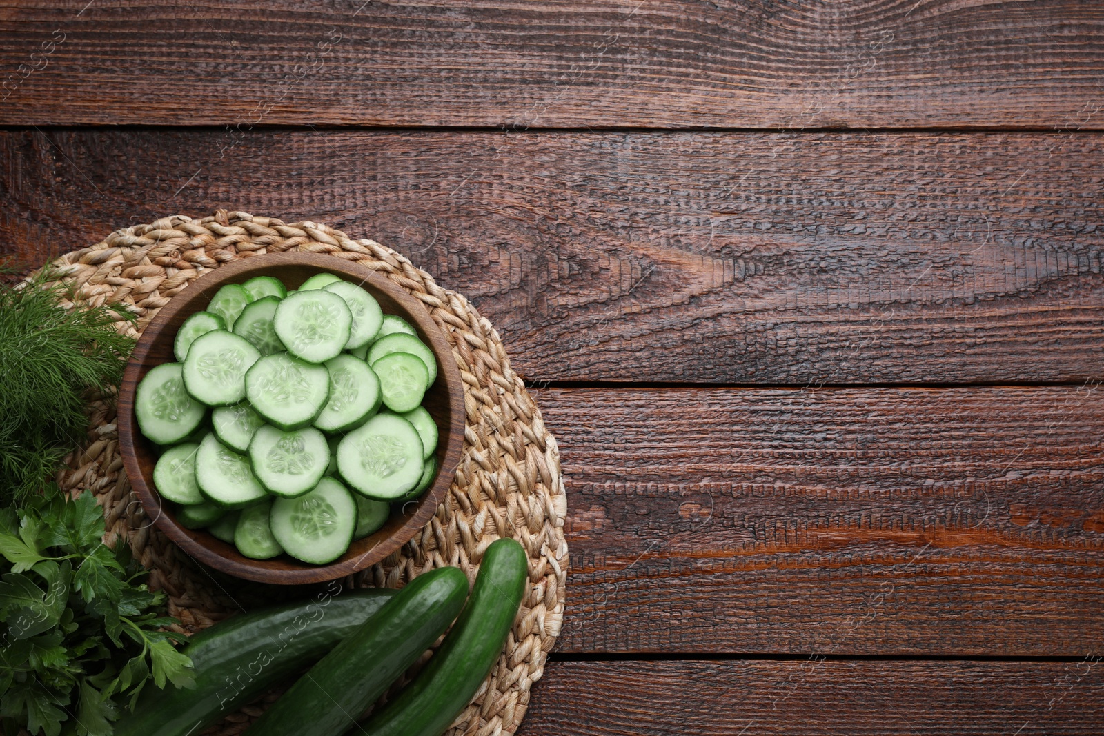 Photo of Fresh ripe cucumbers, dill and parsley on wooden table, top view. Space for text