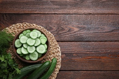 Fresh ripe cucumbers, dill and parsley on wooden table, top view. Space for text