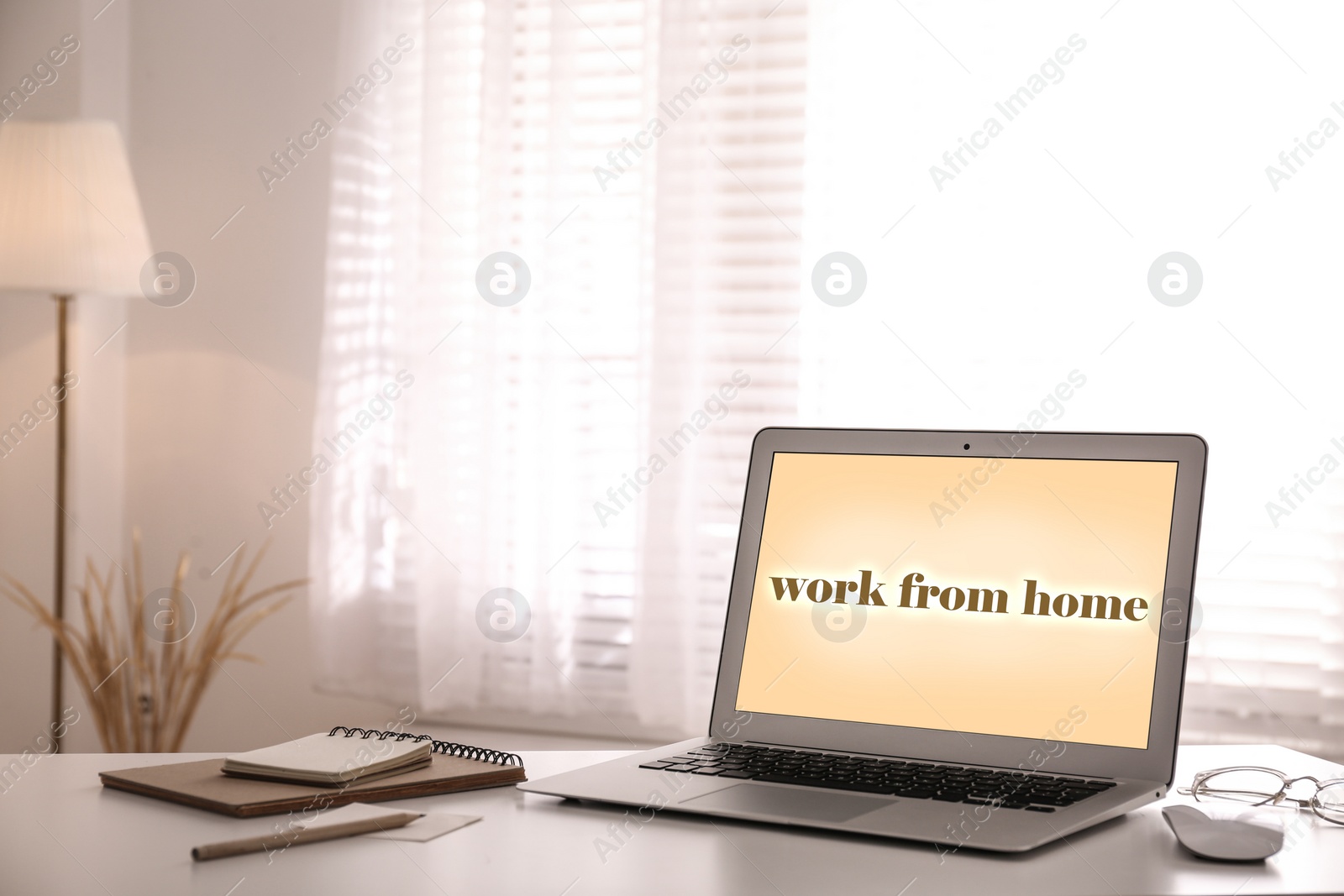 Image of Modern laptop with text WORK FROM HOME on table in office 