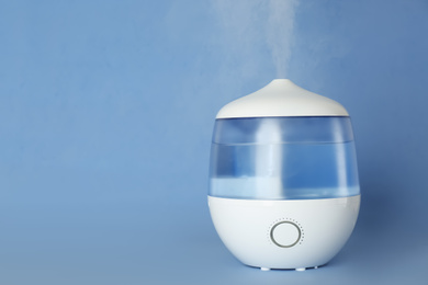 Photo of Modern air humidifier on light blue background. Space for text
