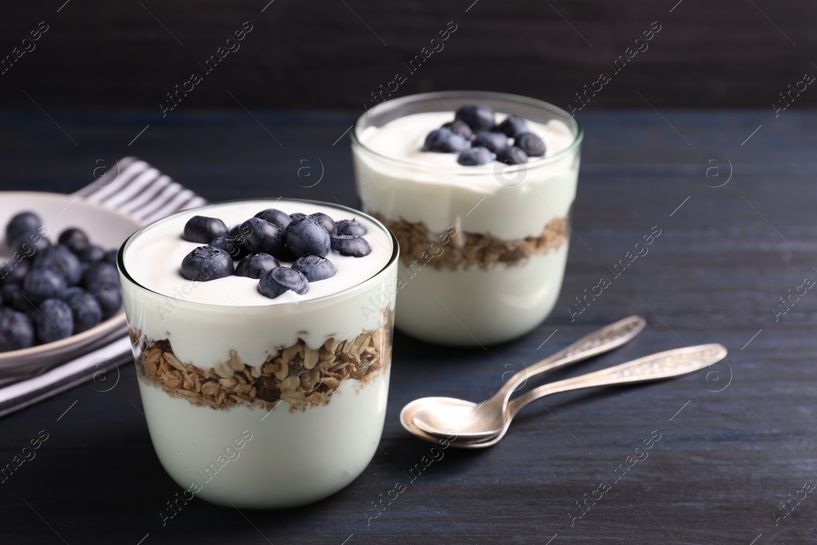 Photo of Glasses with yogurt, berries and granola on table