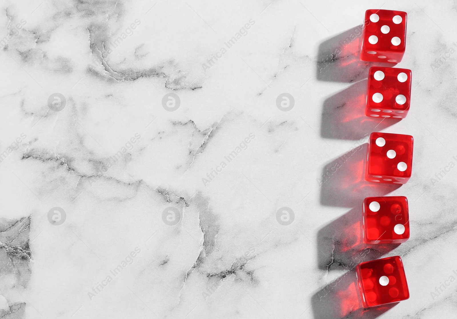 Photo of Many red game dices on white marble table, flat lay. Space for text