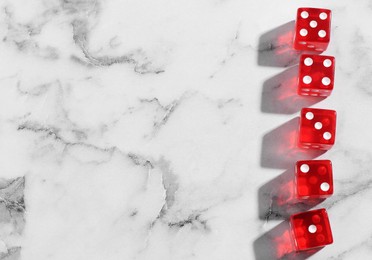 Many red game dices on white marble table, flat lay. Space for text