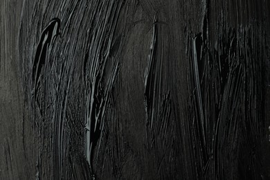 Photo of Beautiful strokes of black paint as background, closeup