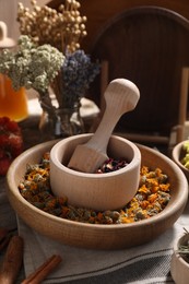 Photo of Mortar with pestle, many different dry herbs and flowers on table