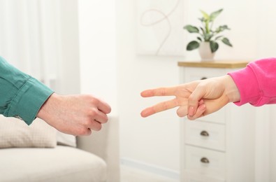 Photo of People playing rock, paper and scissors indoors, closeup