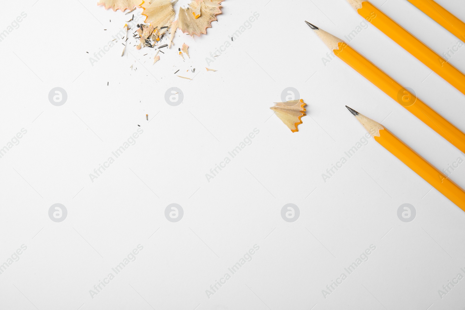 Photo of Graphite pencils and shavings on white background, top view. Space for text