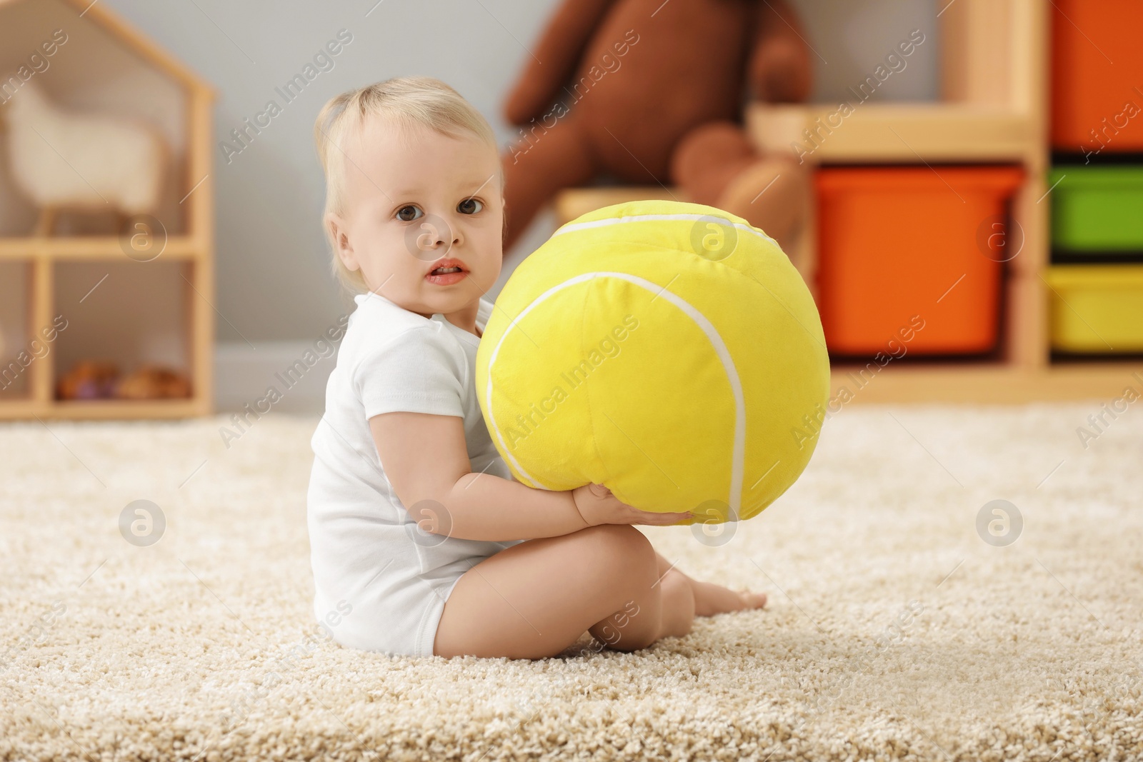 Photo of Children toys. Cute little boy playing with soft toy ball on rug at home