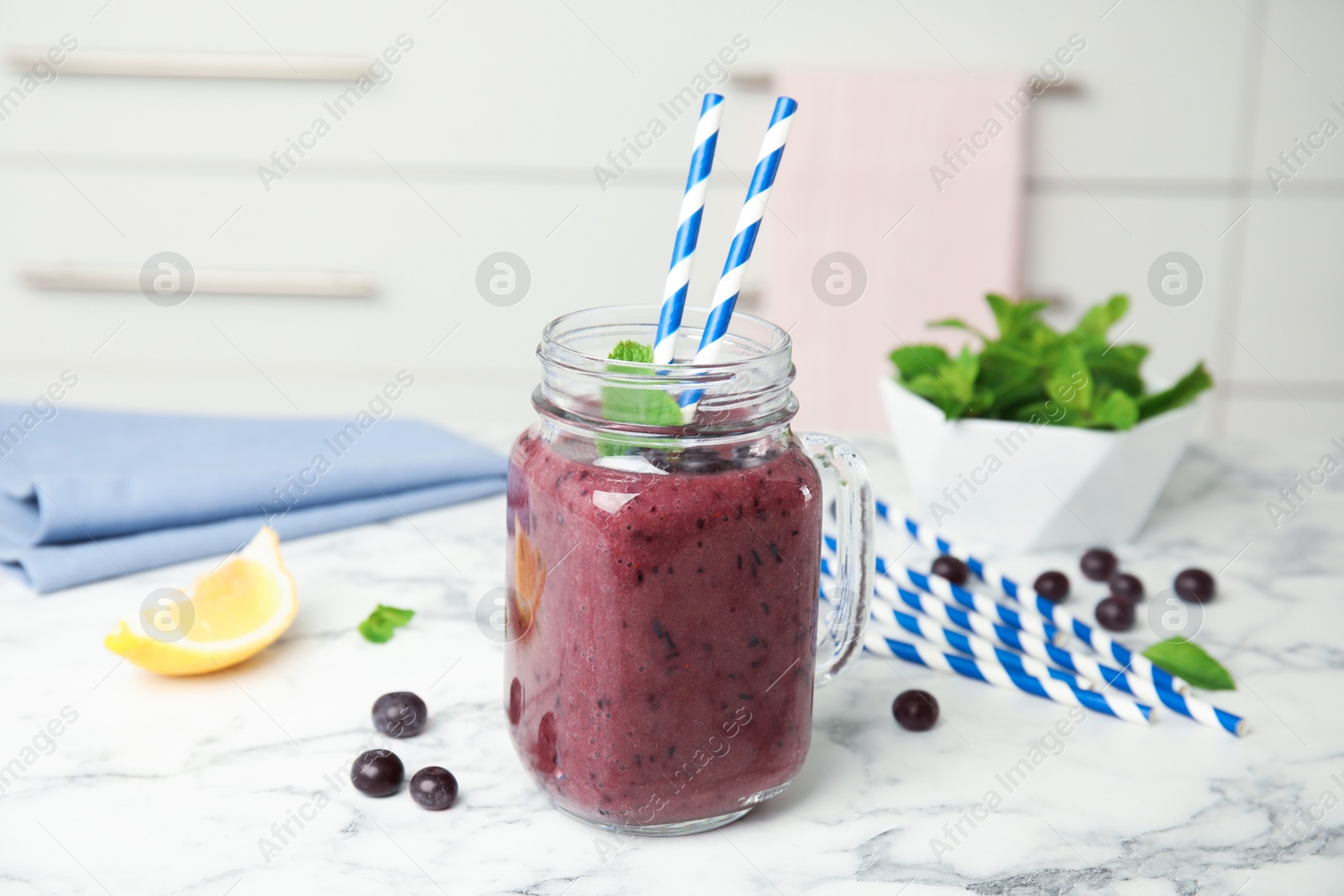 Photo of Mason jar with delicious acai smoothie on table in kitchen