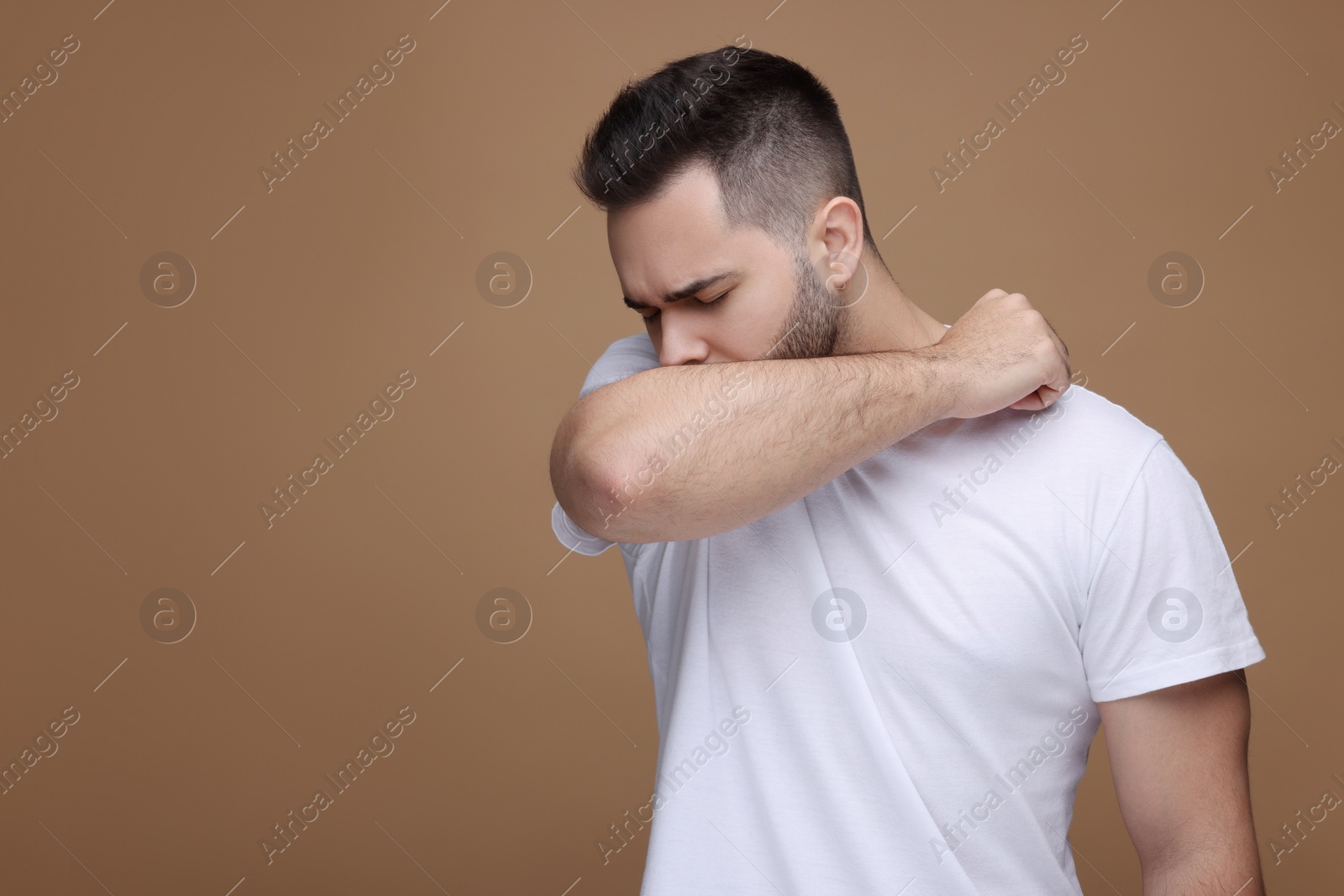 Photo of Sick man coughing on brown background, space for text